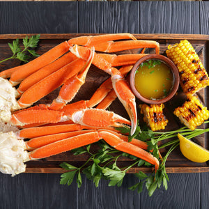 A plate of cooked crab legs with lemon wedges and butter