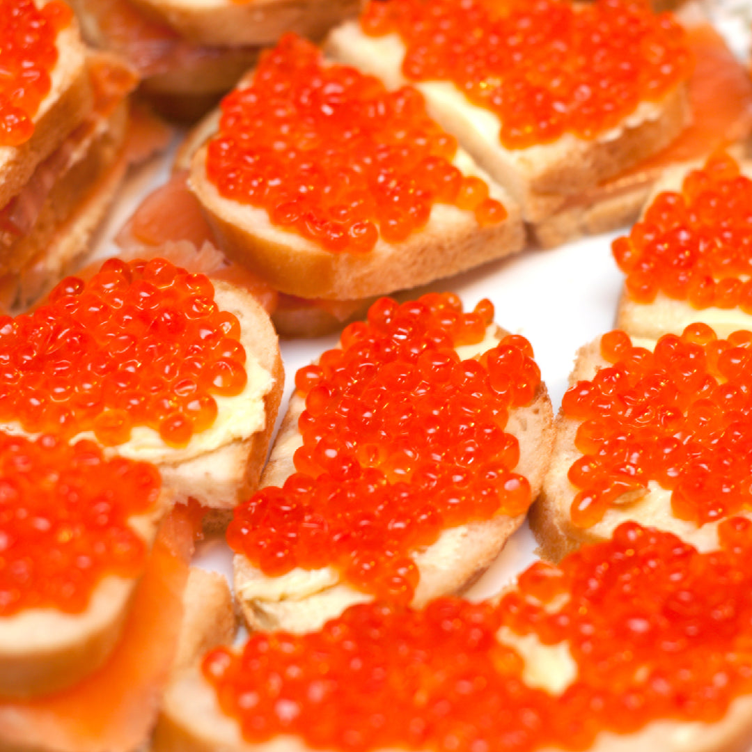 Assorted selection of caviar, including vibrant Ikura and traditional sturgeon varieties, on elegant serving dishes