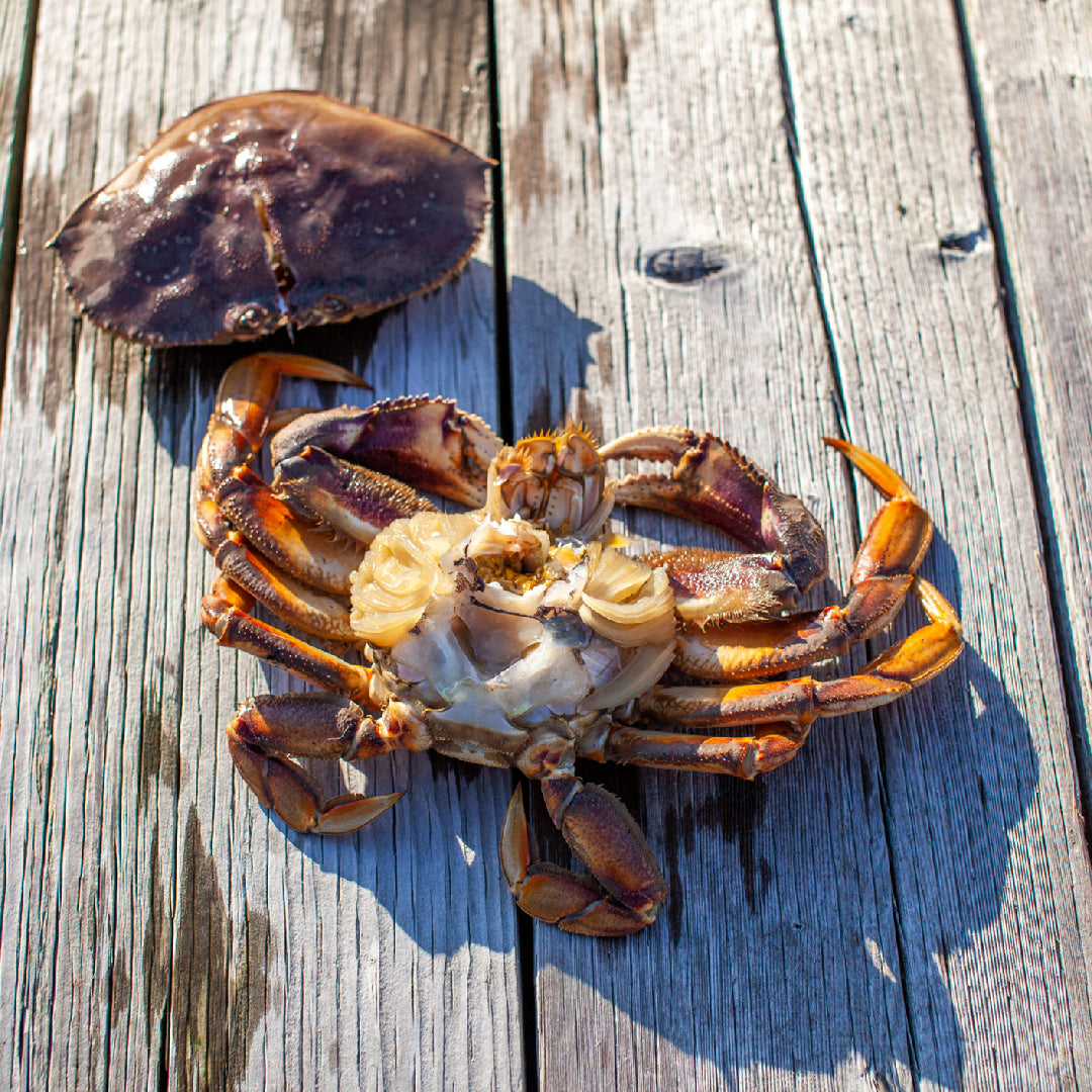 Steamed Dungeness crab legs served with melted butter and lemon wedges on a rustic wooden board