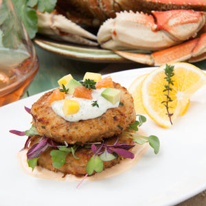 Dungeness Crab Cakes on a plate with lemon wedges and parsley garnish