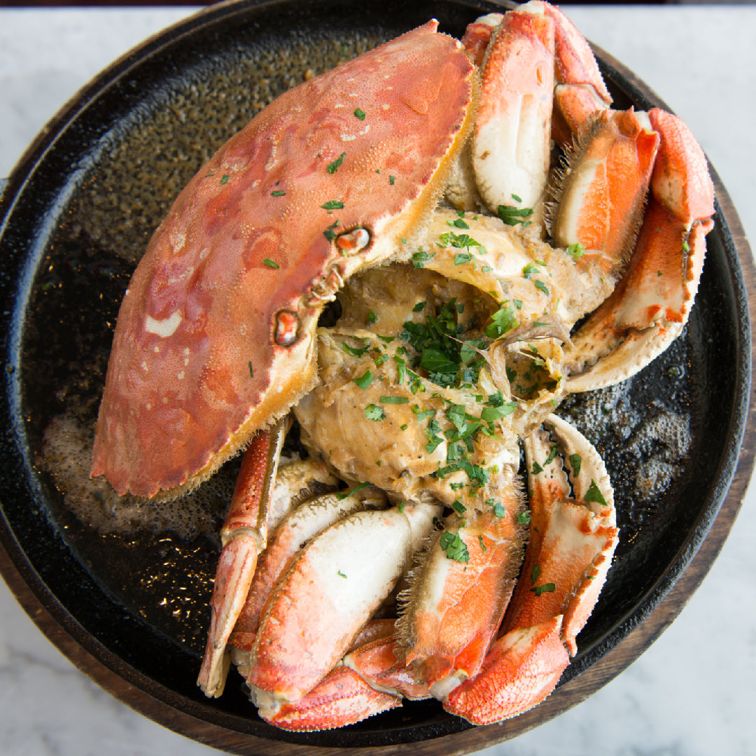 Chilled white wine and steamed Dungeness crab with lemon and garlic butter on a coastal table setting