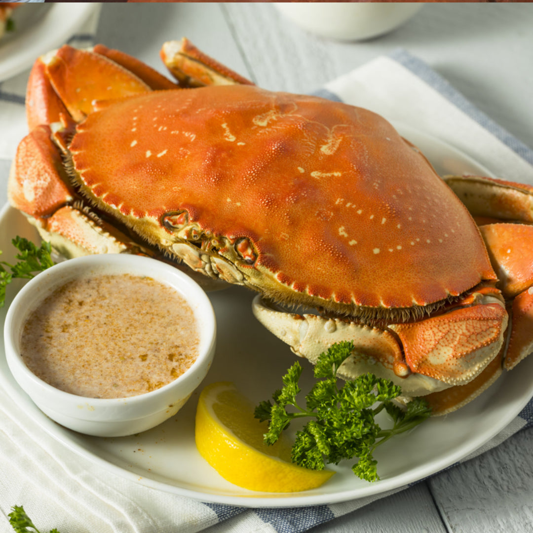 Whole Dungeness crab steamed and cracked open on a platter with drawn butter and lemon — the classic preparation that showcases the sweet, rich flavor of Pacific Coast Dungeness crab