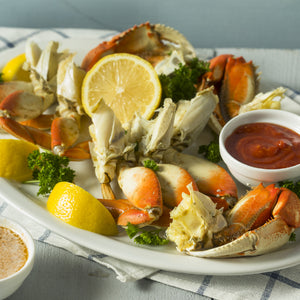 Dungeness Crab on a plate with lemon wedges and herbs
