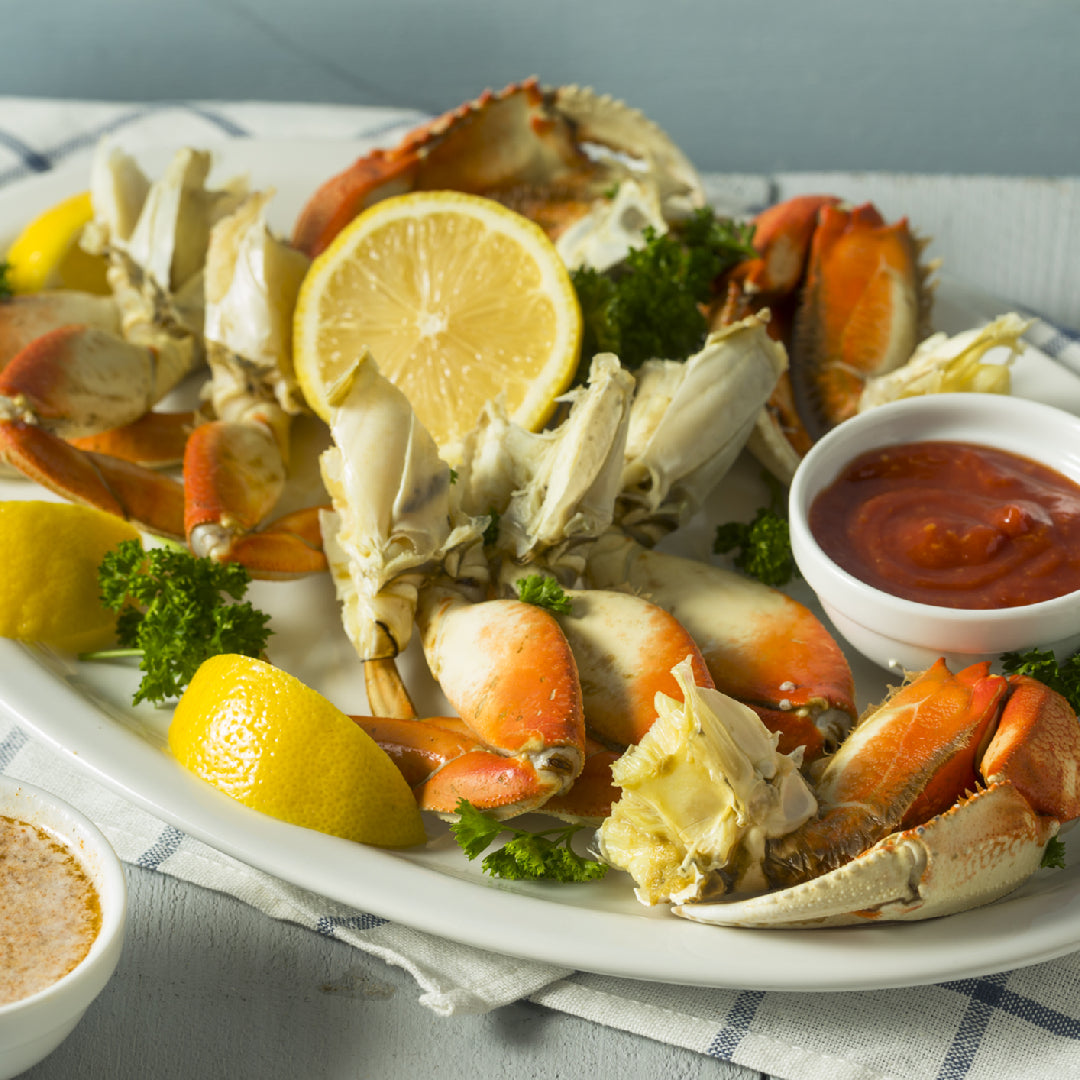 Dungeness Crab on a plate with lemon wedges and herbs