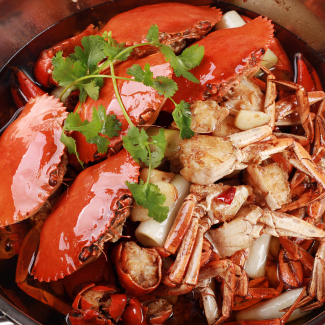 Drunken Dungeness crab stir-fried with garlic, ginger, red chili, and rice wine, garnished with green onions