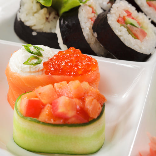 Freshly made red caviar sushi rolls sliced and arranged on a wooden board with soy sauce and chopsticks