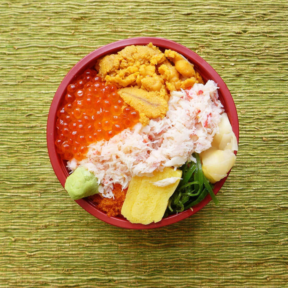 Fresh uni sea urchin roe served as nigiri sushi on a wooden board with soy sauce and wasabi