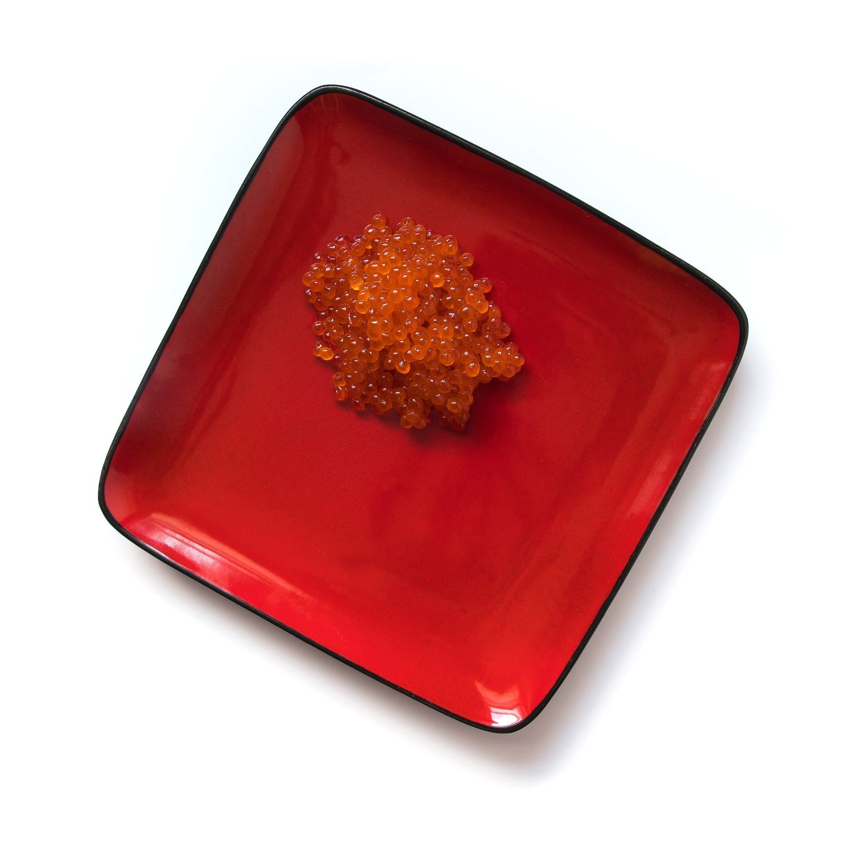 Side-by-side comparison of bright orange salmon roe (ikura) and dark black sturgeon caviar served on blinis with cream