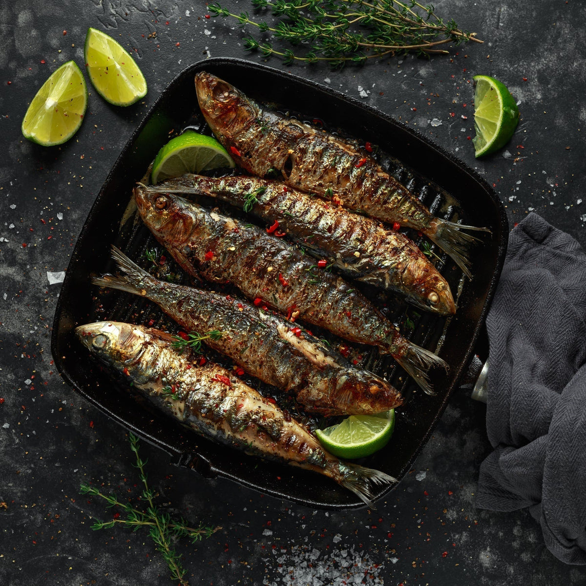 Sardine crostini on toasted baguette slices topped with capers, fresh parsley, and lemon zest arranged on a wooden serving board