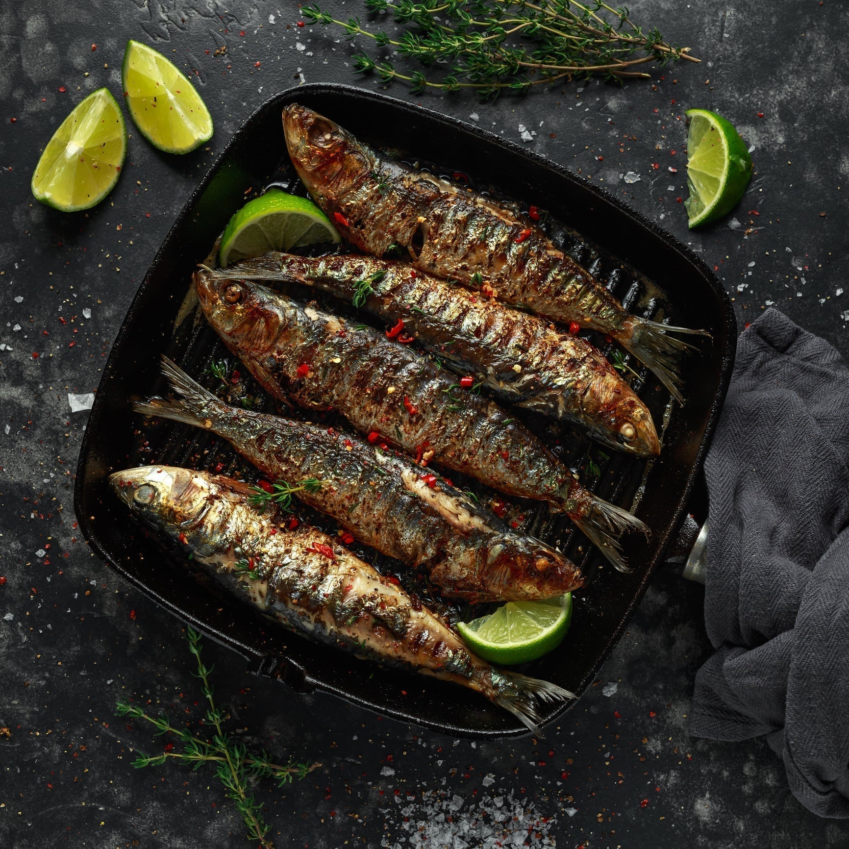 Sardine crostini on toasted baguette slices topped with capers, fresh parsley, and lemon zest arranged on a wooden serving board
