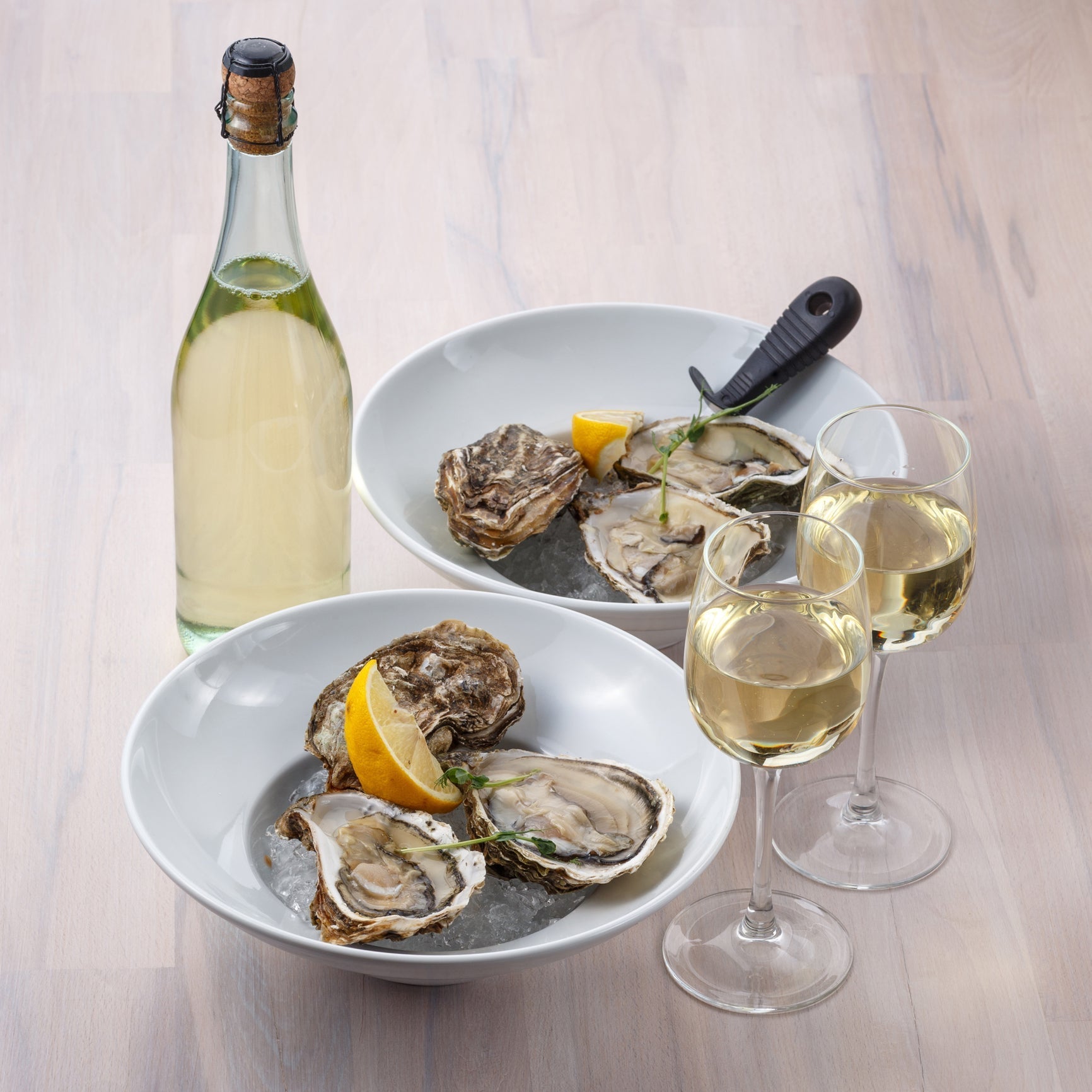 A plate of freshly shucked oysters on ice with lemon wedges and mignonette sauce at a seafood bar during happy hour