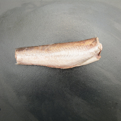 Pacific whiting hake fish fillet on a plate with lemon and fresh herbs