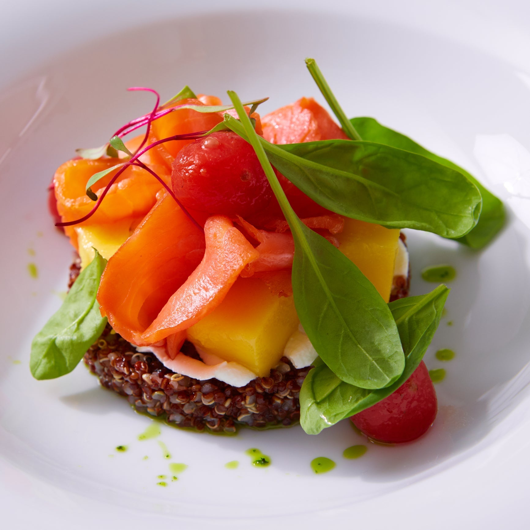 Thick Ora King salmon fillet with vibrant orange-red flesh and visible fat marbling on a dark slate board with fresh herbs