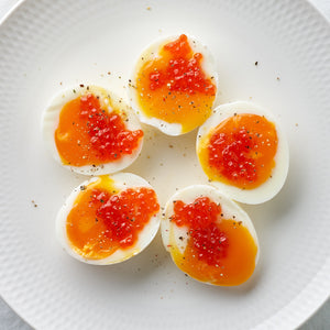 Red caviar deviled eggs on a plate with a sprig of dill on top