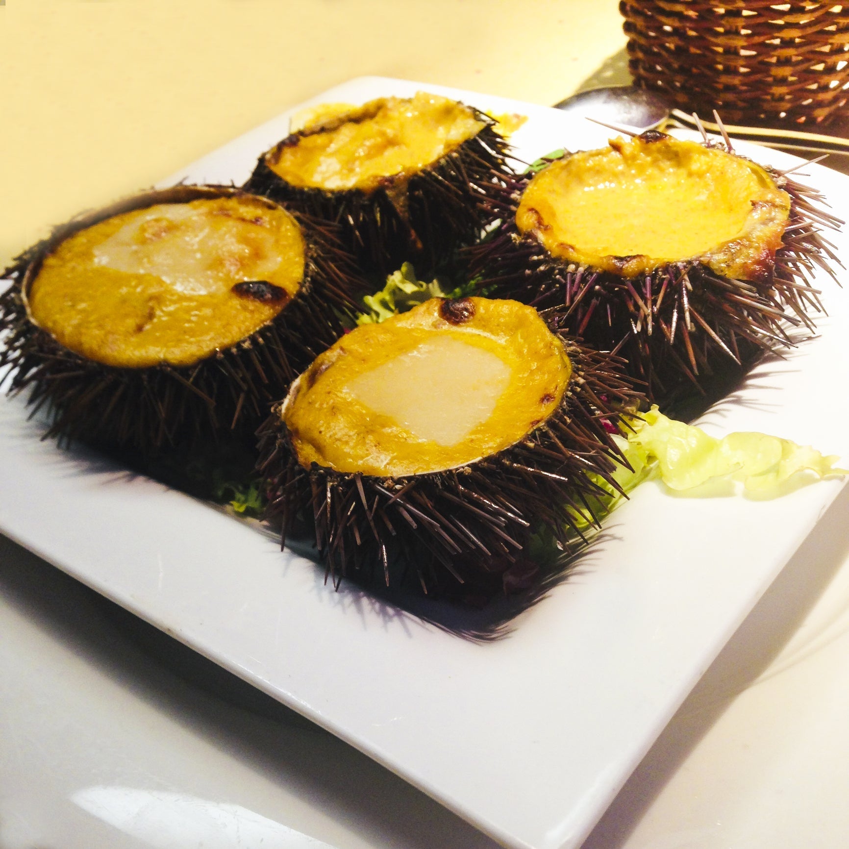 Spicy sea urchin uni nigiri sushi drizzled with sriracha mayo on a dark slate plate
