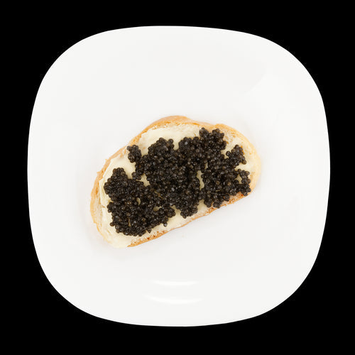 Black caviar served on blinis with crème fraîche alongside fresh greens for a balanced meal