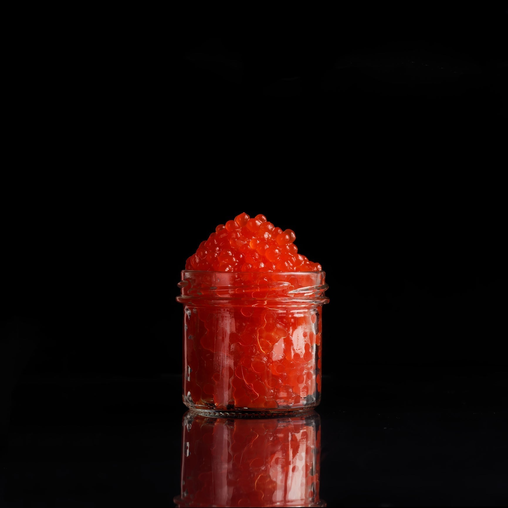 Fresh wild salmon roe (ikura) in a small bowl — large, glossy orange pearls from wild Alaskan Chum salmon, showing the vibrant color and translucency that indicate high-quality, properly cured roe