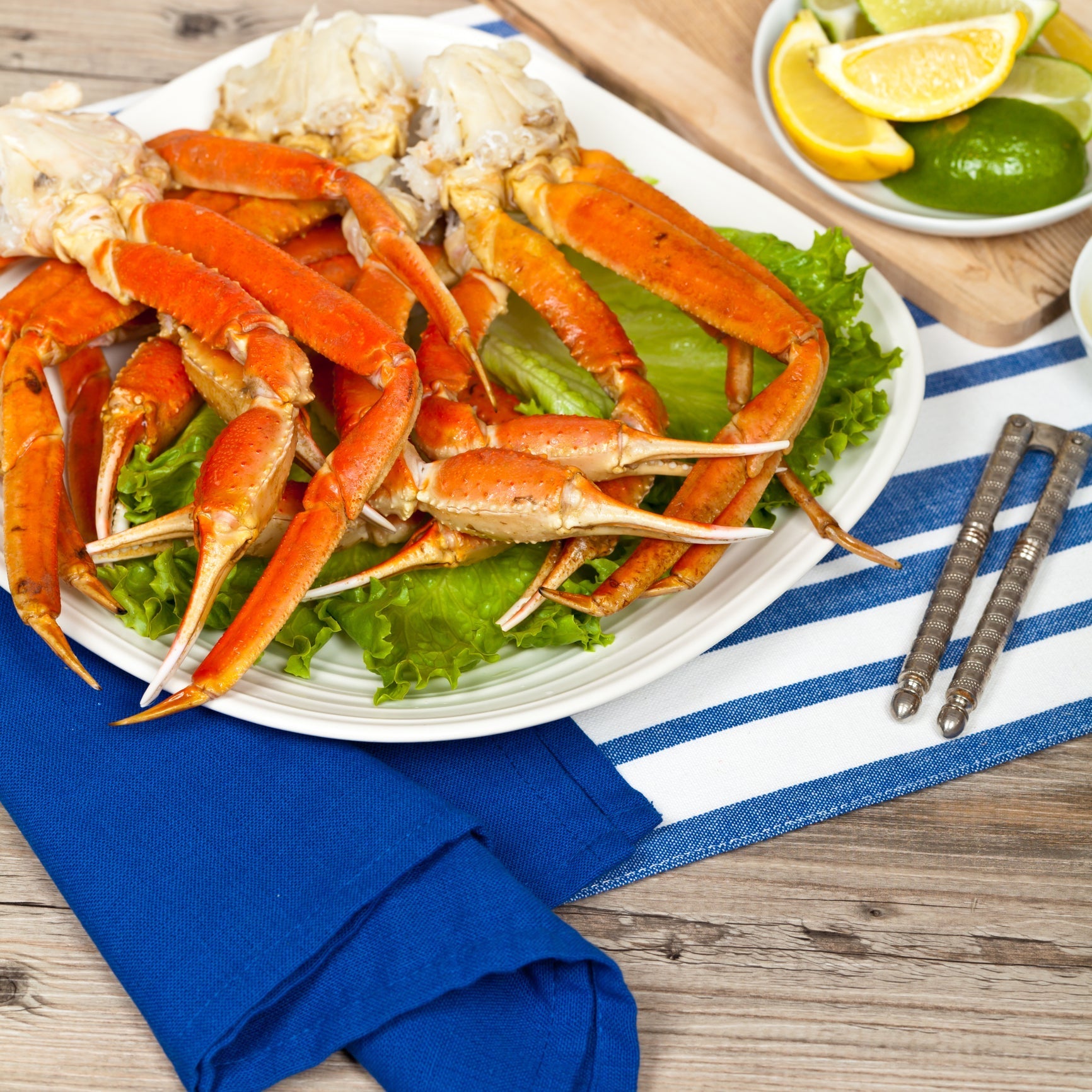 Side-by-side comparison of cooked Dungeness crab and snow crab legs on a serving board with lemon and butter