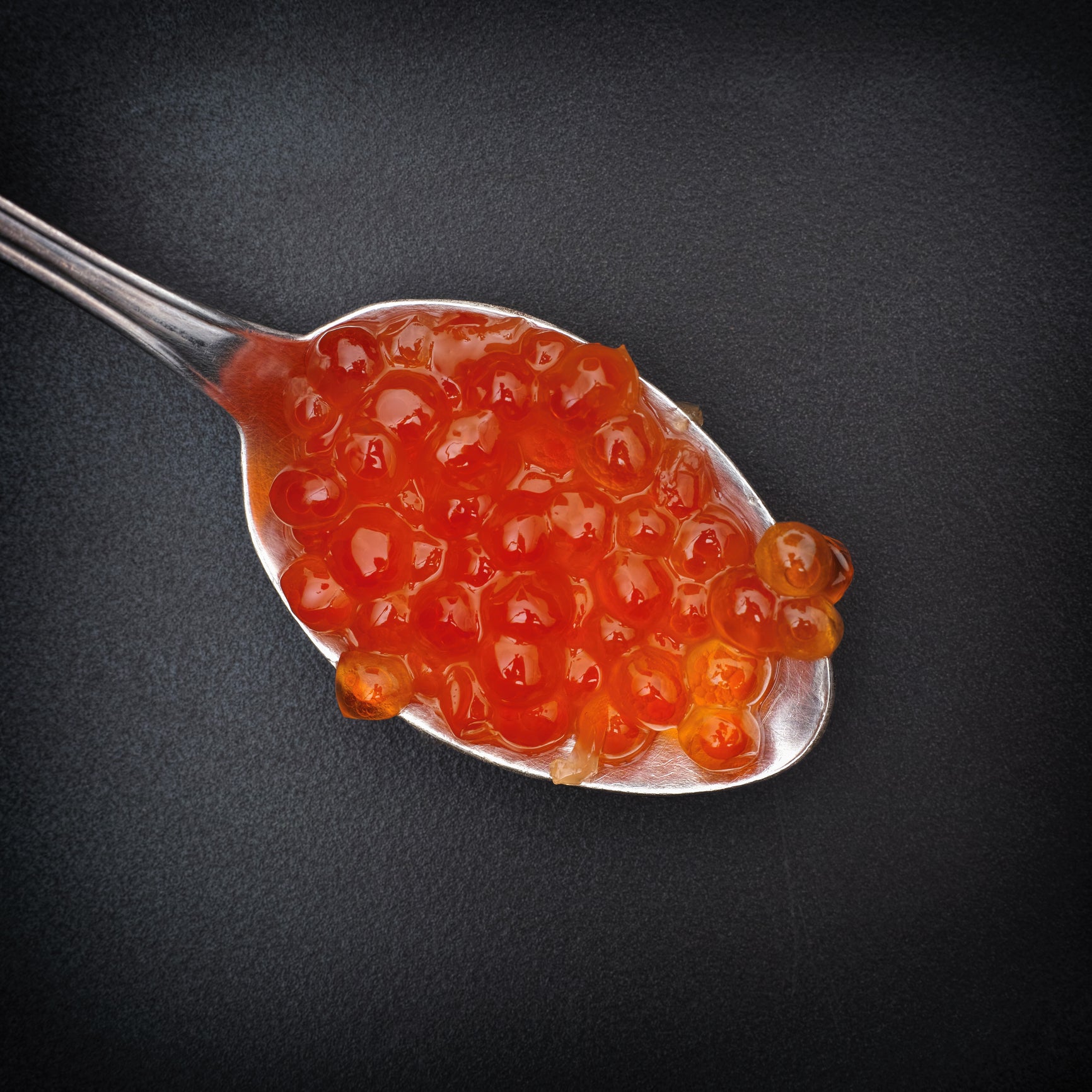 High-quality red caviar in a glass jar with a silver spoon