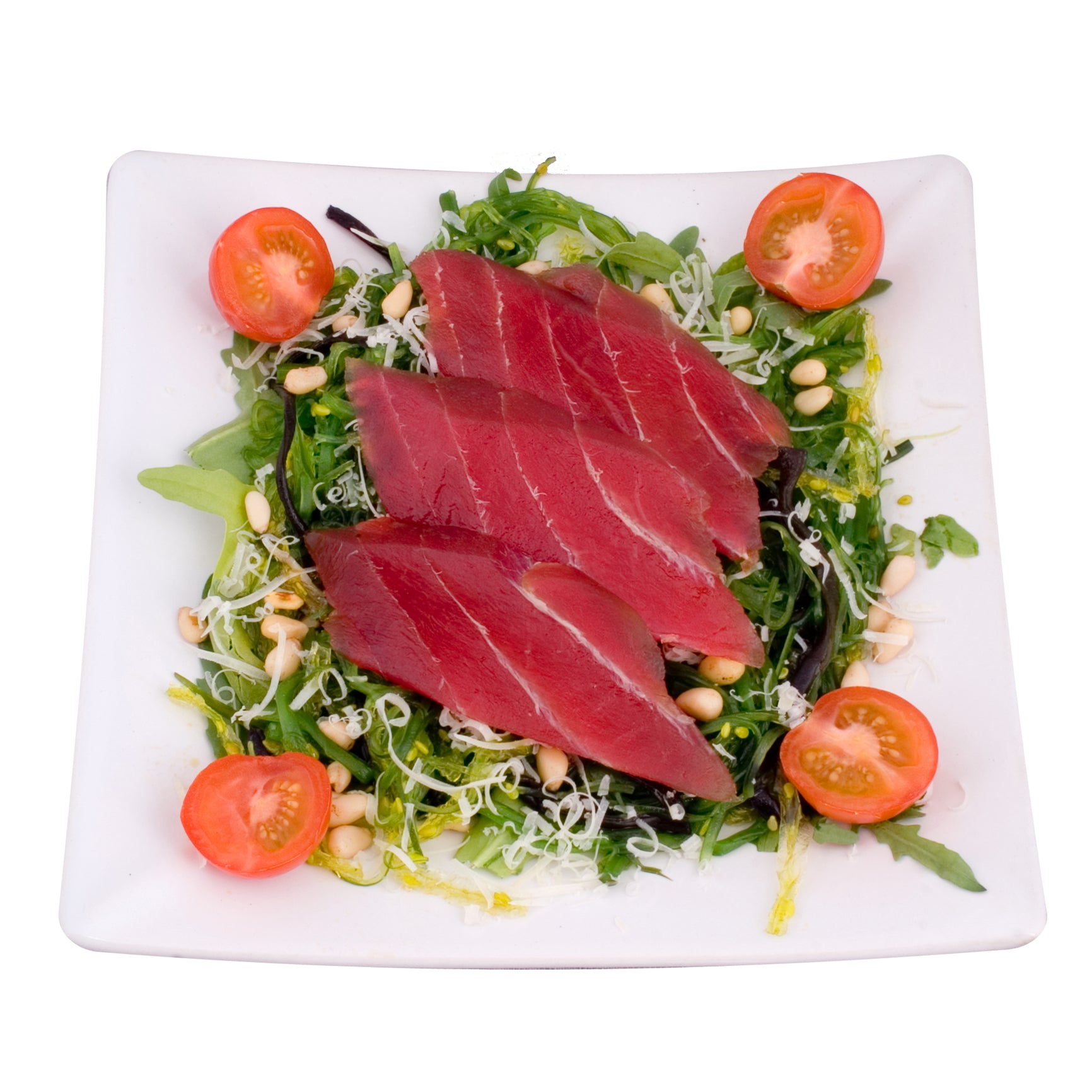 Sliced tuna sashimi on a white plate with fresh green salad
