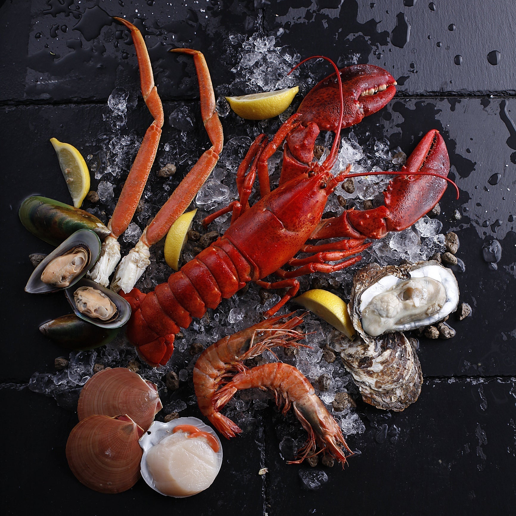 Side-by-side comparison of cooked crab and lobster on a serving platter with lemon wedges