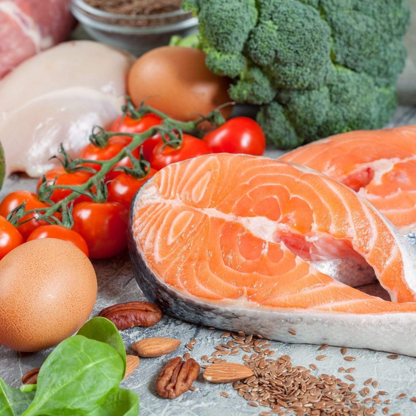 Top 10 low carb foods including salmon, caviar, shrimp, eggs, avocado, and leafy greens on a wooden board