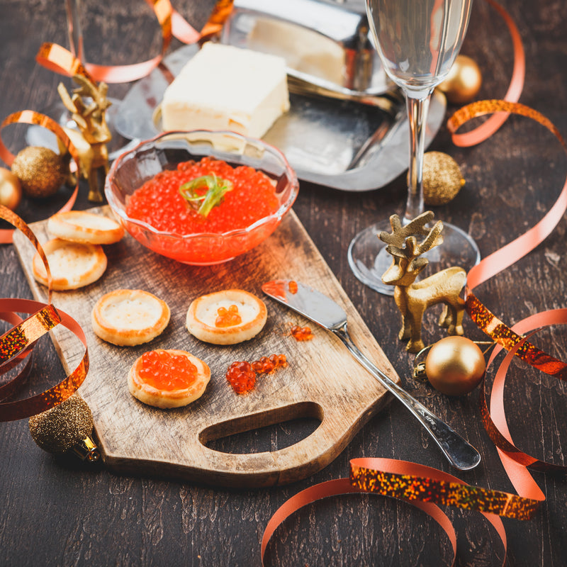 Elegant caviar serving presentation on crushed ice with blinis, crème fraîche, and champagne