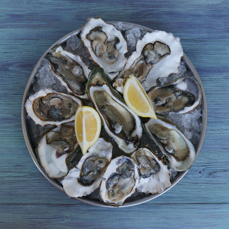 Fresh raw oysters on the half shell served on ice with lemon wedges and mignonette sauce