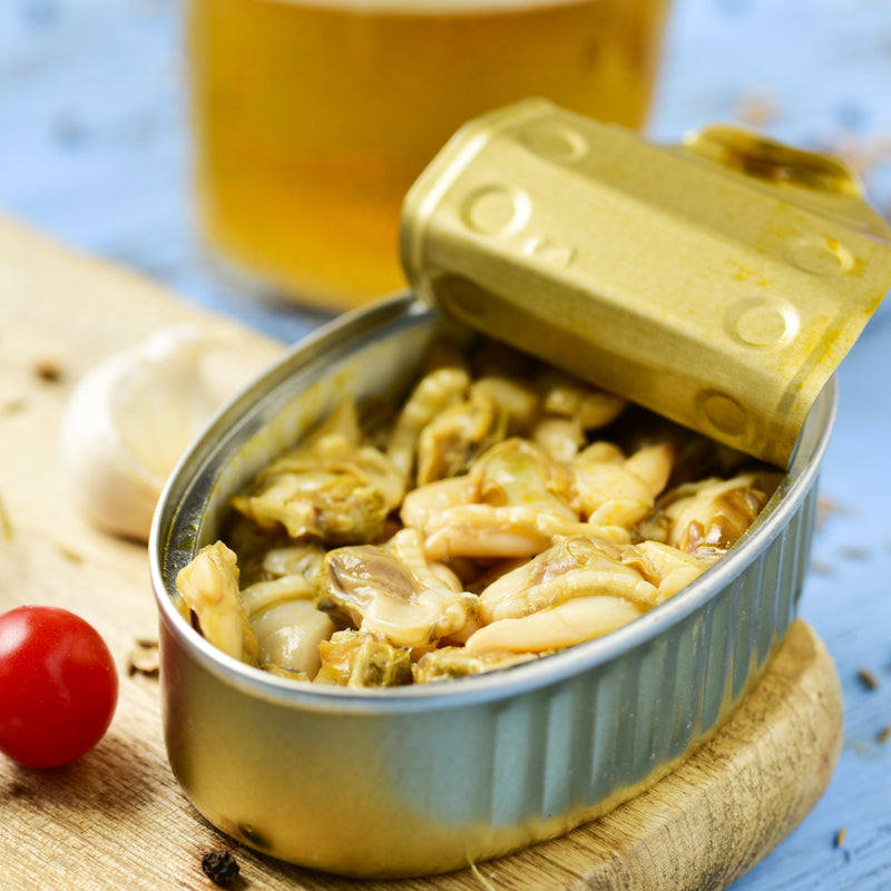 Open can of clams with fresh clam chowder and linguine with clam sauce in the background