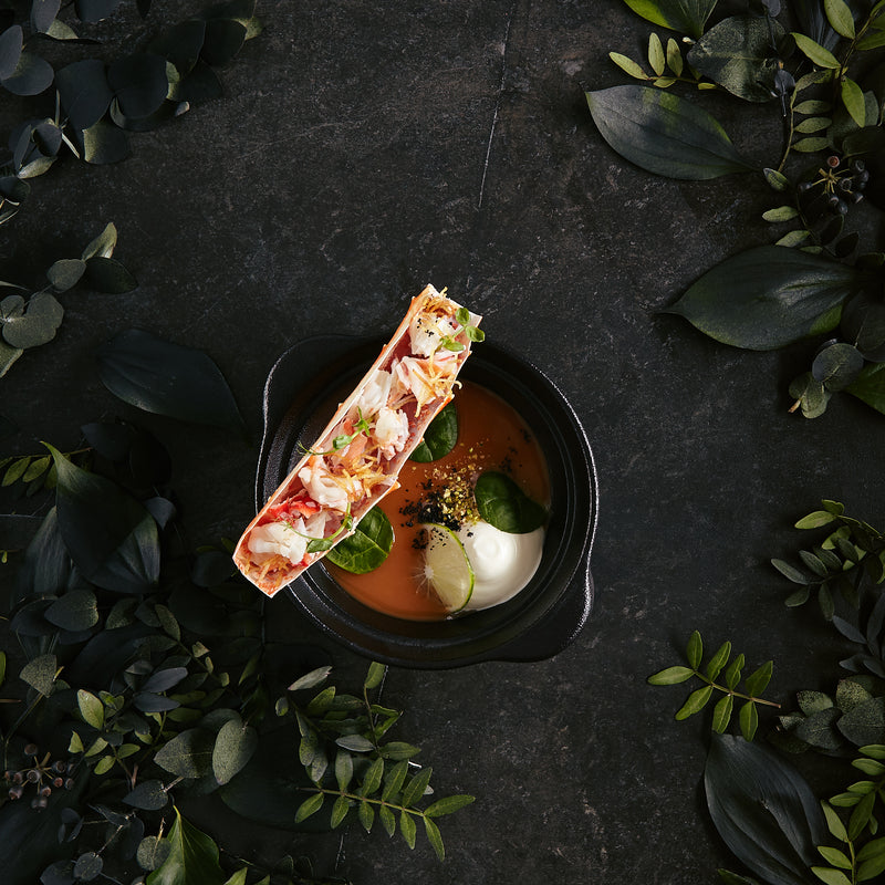 Rich golden lobster stock simmering in a large pot with lobster shells, vegetables, and herbs