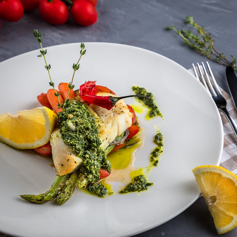Wild Alaskan halibut fillet pan-seared golden brown with lemon butter sauce and fresh parsley on a white plate