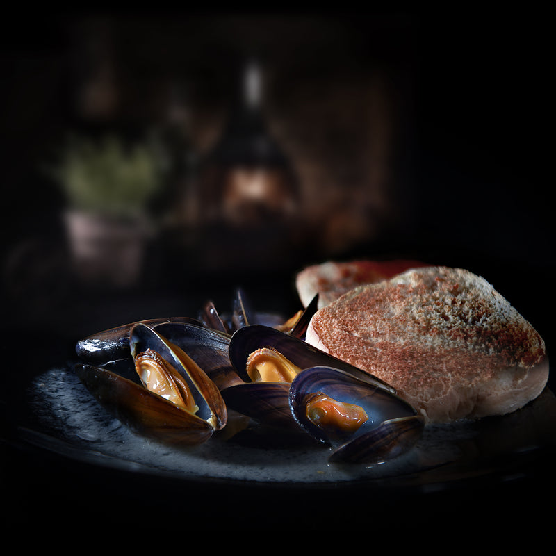 Fresh steamed mussels in a bowl with garlic, herbs, and lemon