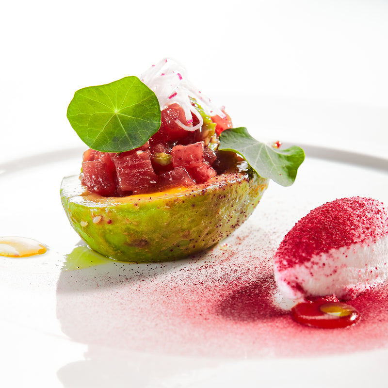 Gourmet smoked tuna tartare served in a ring mold on a bed of microgreens with sesame seeds, soy sauce, and crispy crostini