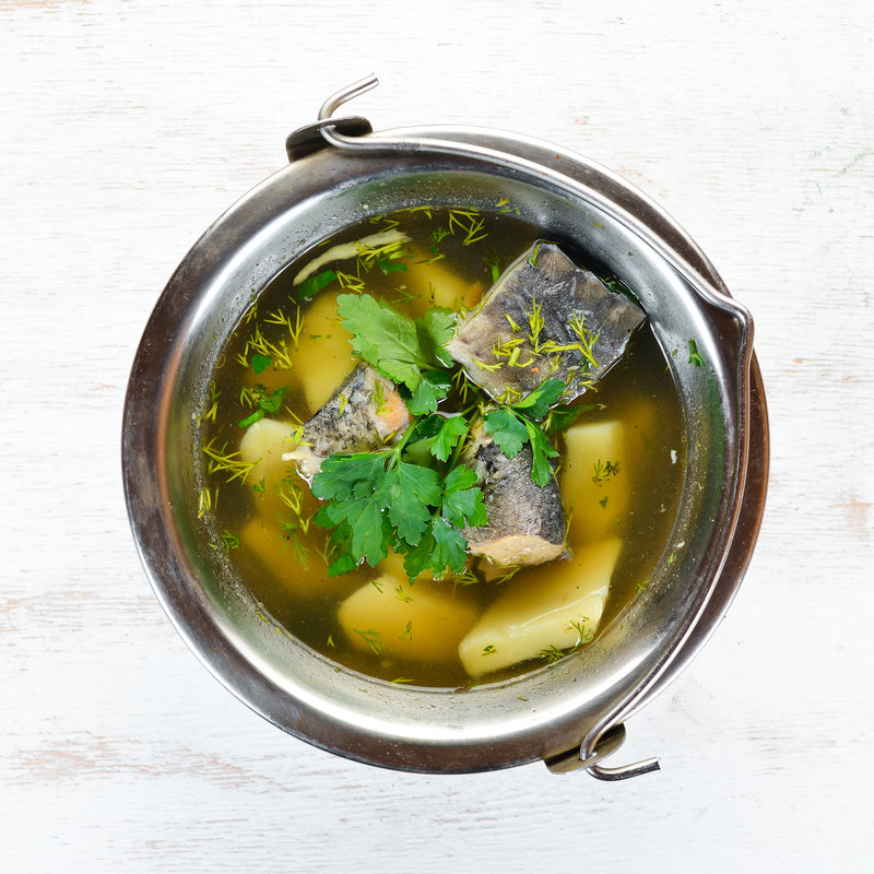 Hearty fish soup with cod, carrots, potatoes, and fresh herbs in a rustic bowl