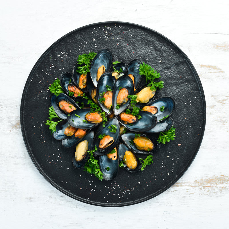 Steamed mussels in white wine cream sauce with parsley in a large pot