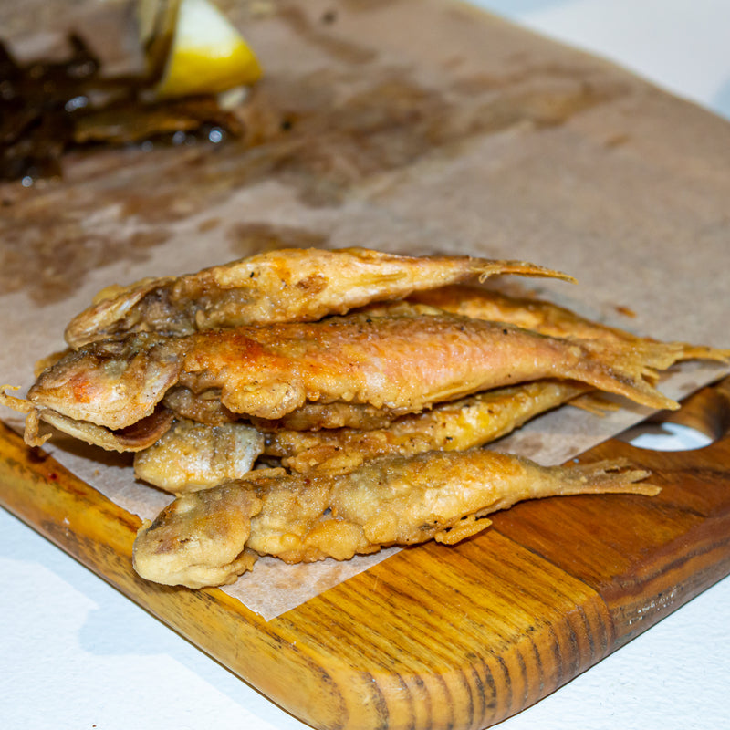 A golden, crispy pan-fried fish fillet served on a white plate with lemon wedges and fresh parsley, exemplifying the delicious outcome of the perfect fried fish recipe