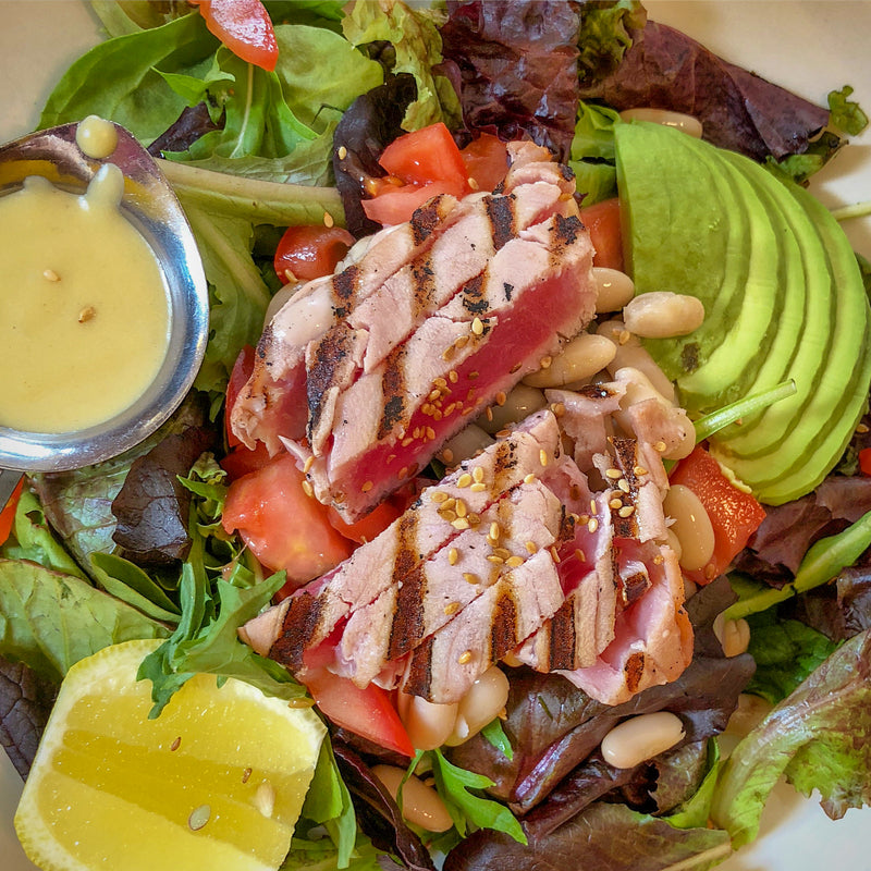 Smoked tuna platter with crostini, avocado, and garnishes on a rustic wooden table
