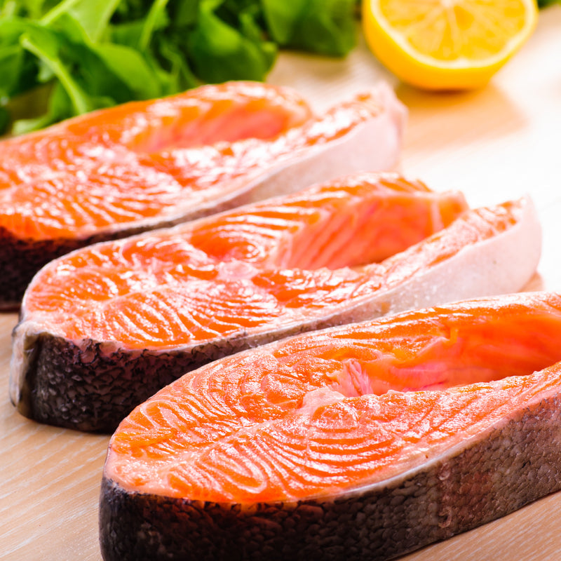 Dry aged King Salmon steaks baked with colorful roasted vegetables on a baking tray
