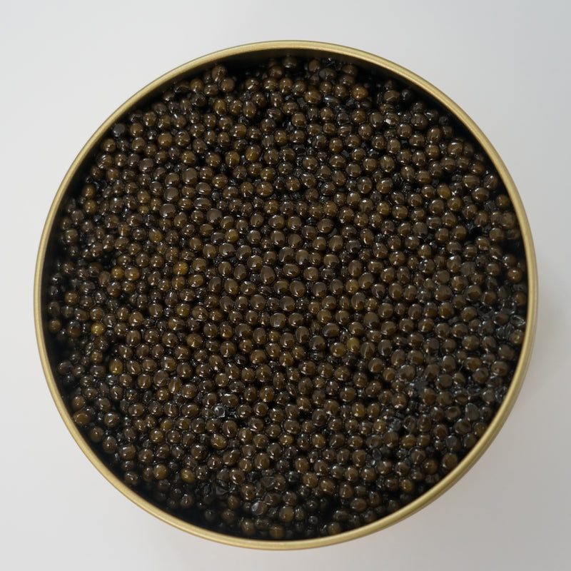 Paddlefish caviar served in a glass bowl with blinis and crème fraîche