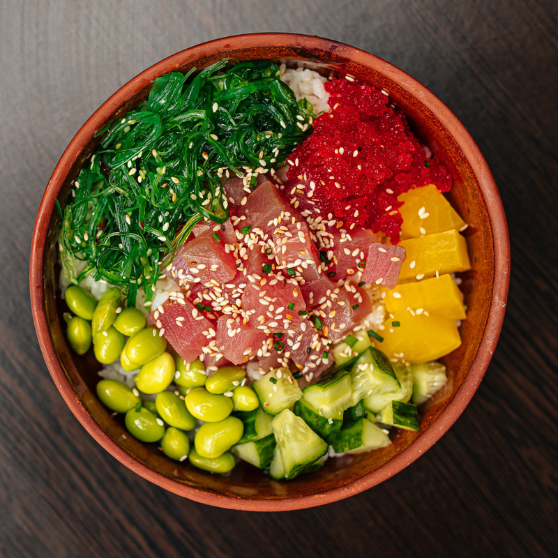 Hawaiian poke tuna bowl with cubed ahi tuna, edamame, mango, avocado, and sesame seeds over steamed rice