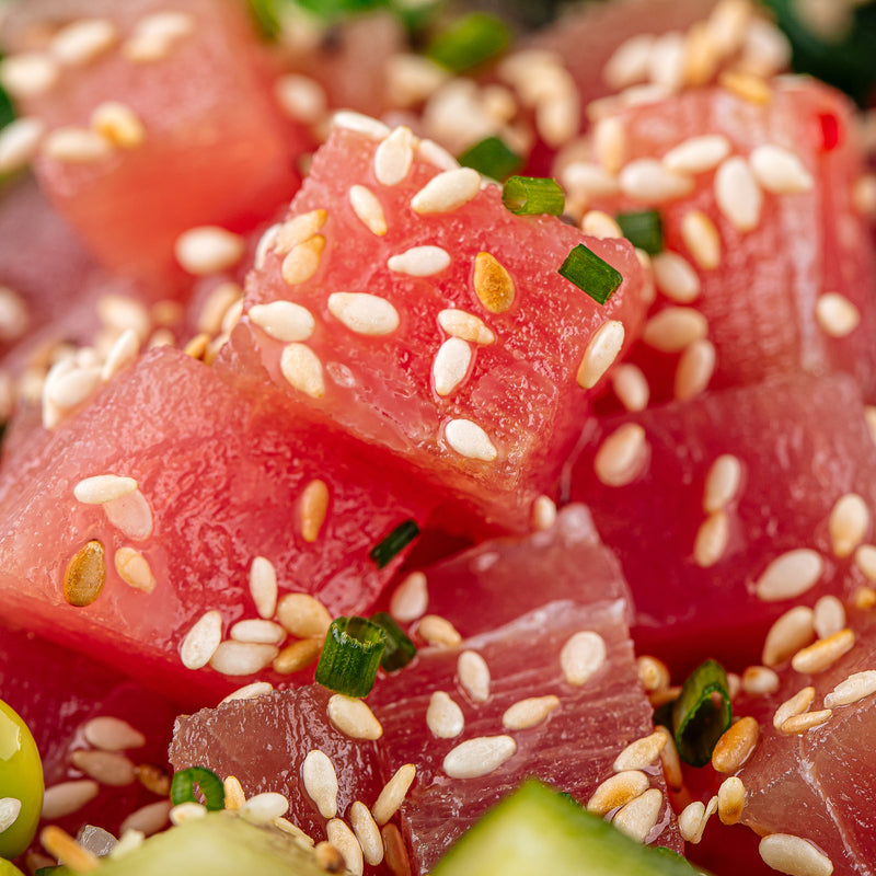 Colorful poke tuna bowl with cubed ahi tuna, edamame, avocado, mango, and sesame seeds over white rice