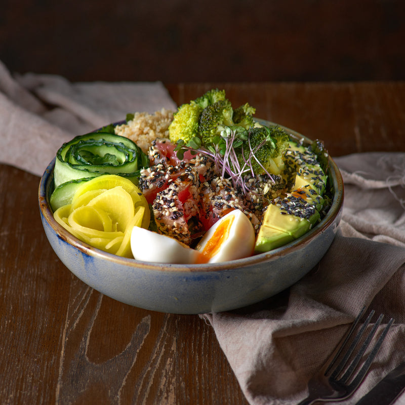 Colorful poke tuna bowl with fresh ahi tuna, avocado, cucumber, seaweed salad, and sesame seeds on a bed of steamed rice