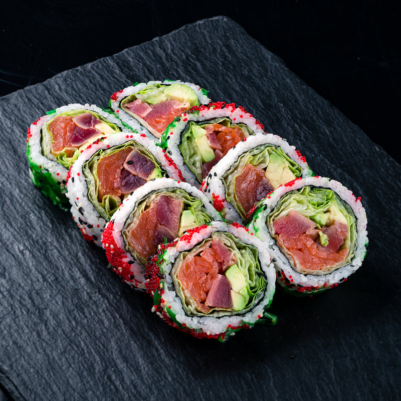 Sliced smoked tuna fillet on a wooden board with herbs and lemon wedges