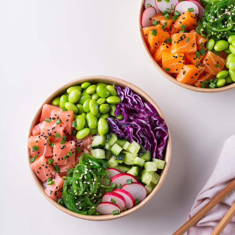 Side-by-side comparison of a Hawaiian poke tuna bowl and a Japanese sushi platter with nigiri and maki rolls