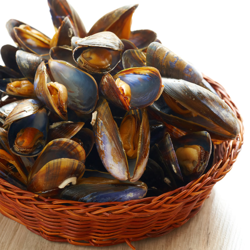 Fresh steamed mussels in a white wine and garlic broth, garnished with fresh parsley and lemon wedges