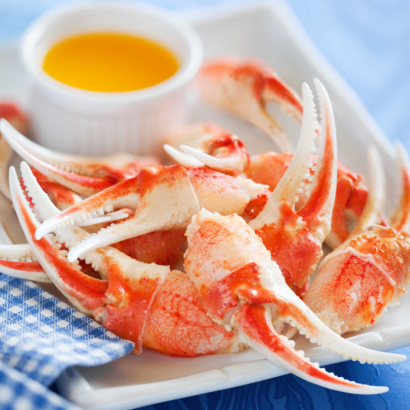 Side-by-side comparison of king crab legs and snow crab clusters on a seafood platter with lemon wedges