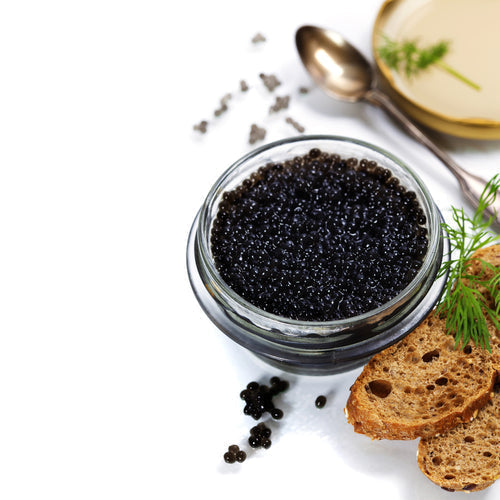 Fresh sturgeon roe caviar pearls in a traditional tin surrounded by ice and a mother-of-pearl spoon