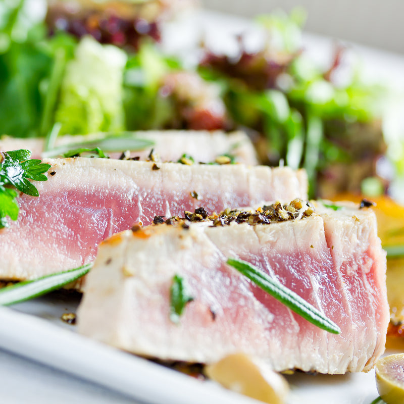 Smoked tuna party platter with colorful vegetables, dips, and garnishes on a wooden board
