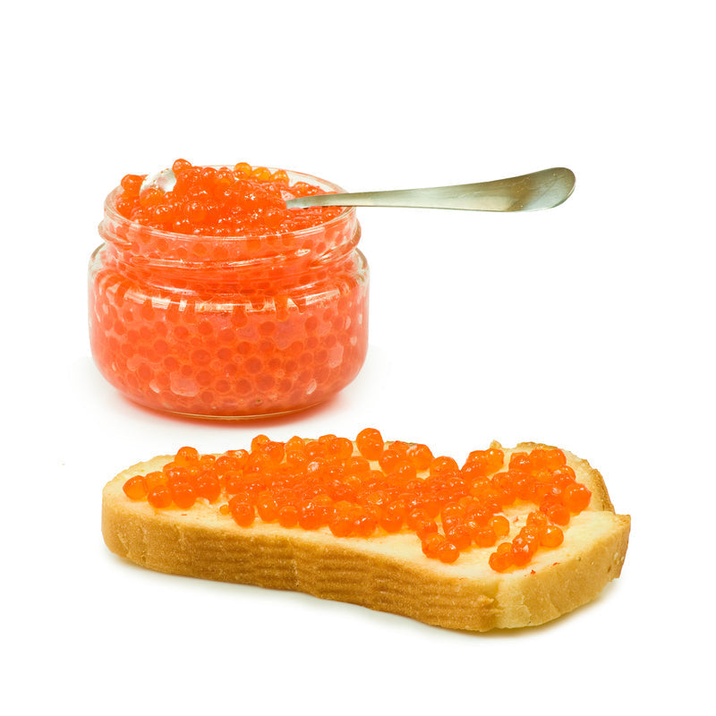 Close-up of vibrant orange salmon roe eggs in a glass jar on a dark wooden surface