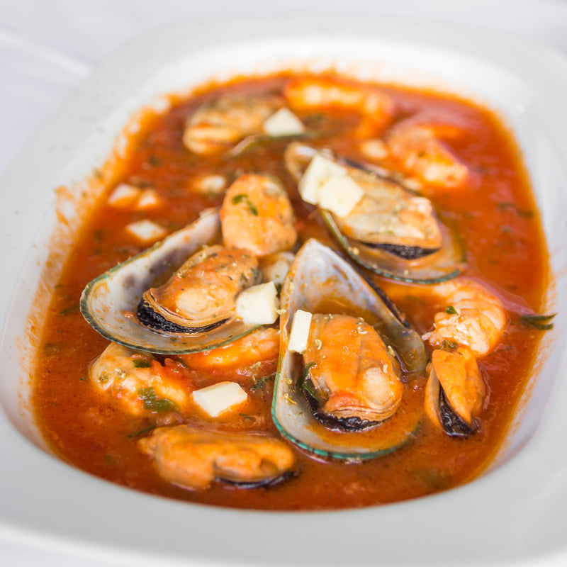 Steamed mussels in white wine sauce alongside clams, shrimp, and oysters on a seafood platter